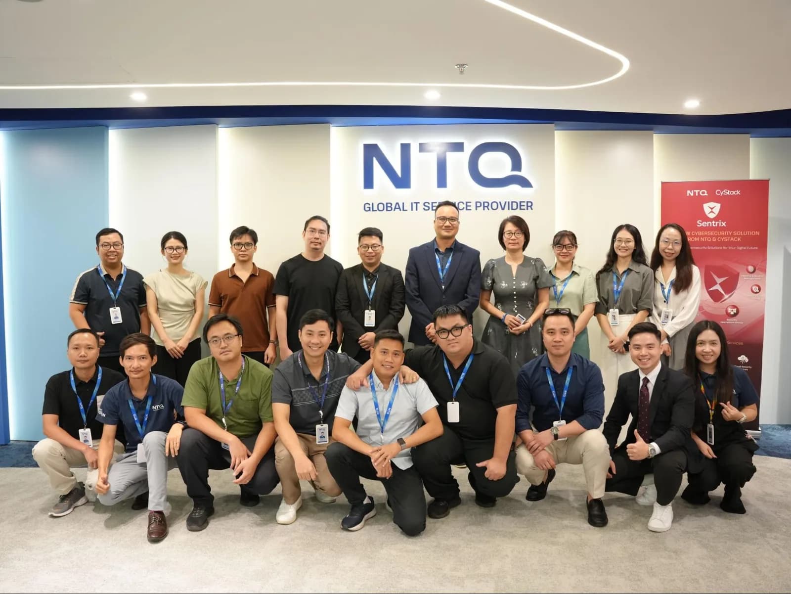 Đội ngũ nhân sự NTQ và CyStack chụp ảnh chung trước logo NTQ và standee Sentrix